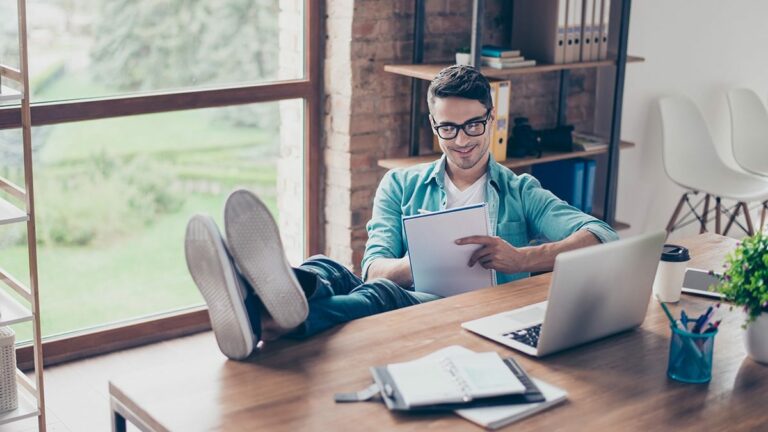 portrait-of-smiling-freelancer-sitting-at-home-in-front-of-compu